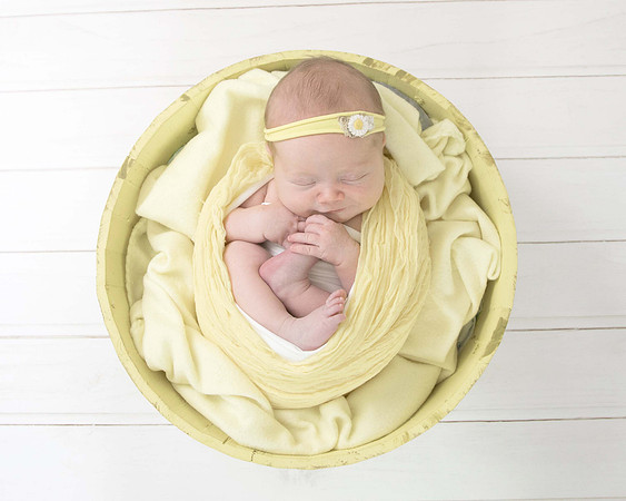 Newborn baby girl in yellow in basket